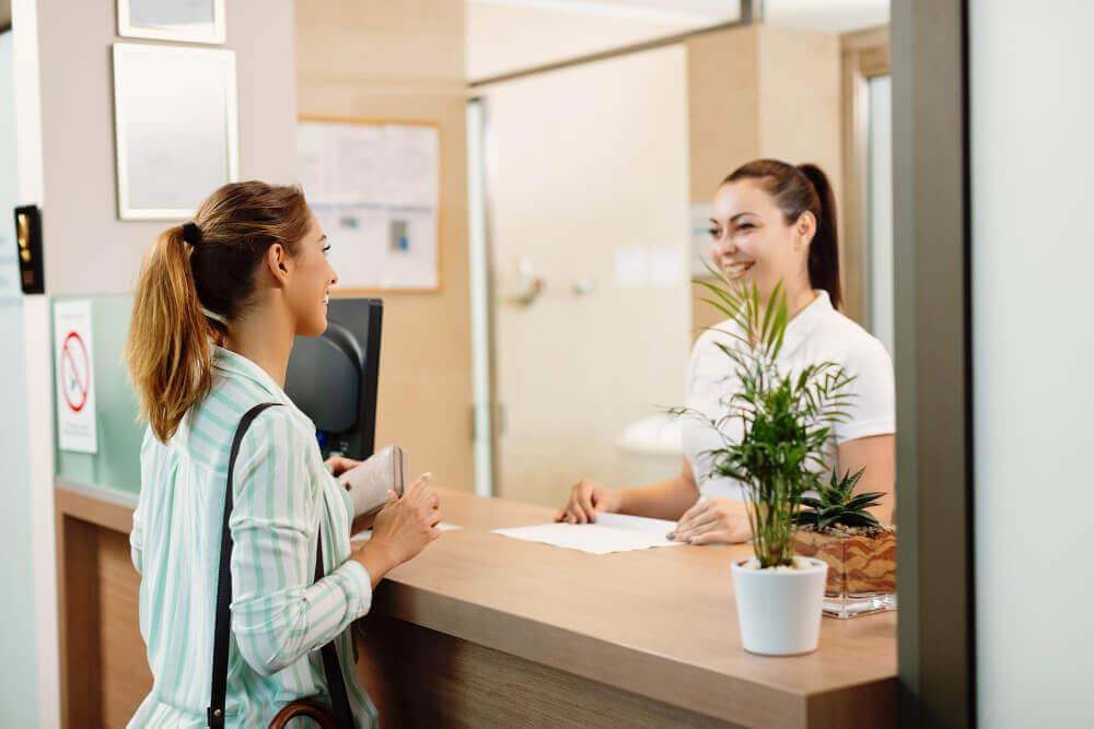 happy-woman-talking-receptionist-while-arriving-spa (1)